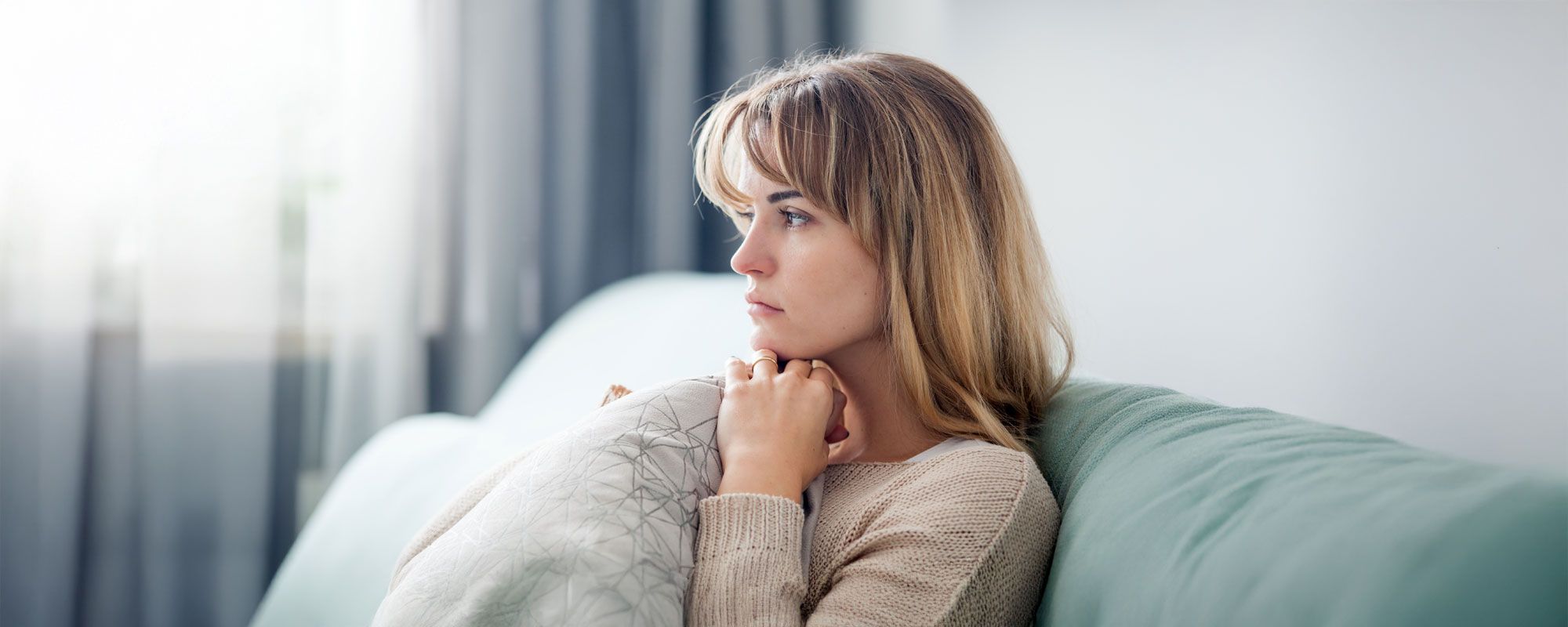 Nachdenkliche Frau auf Sofa.