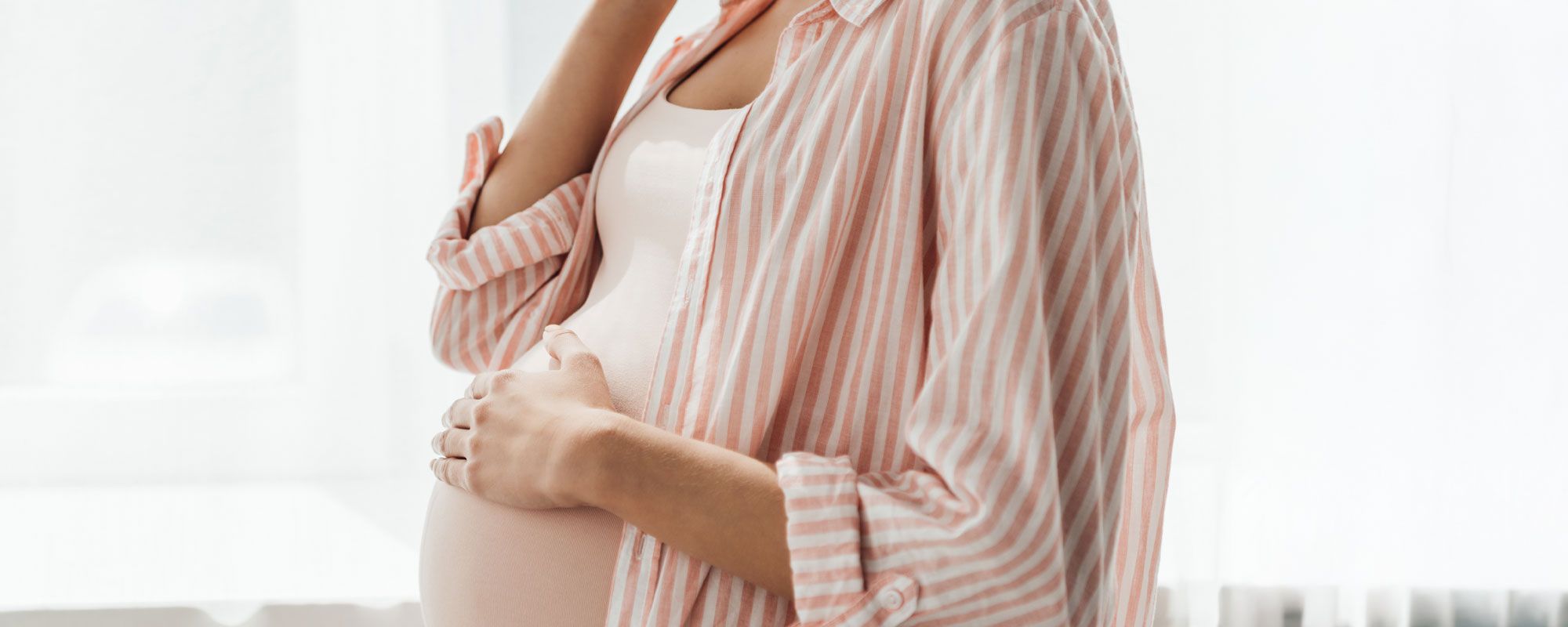 Schwangere Frau hält ihren Bauch.