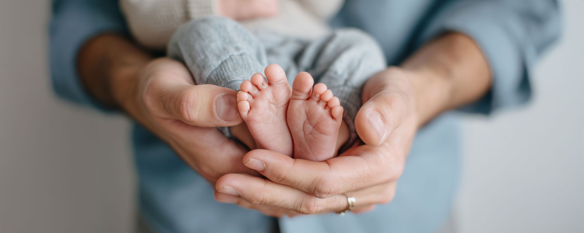 Ein Elternteil hält die Füße eines Babys. Babfüße in Händen